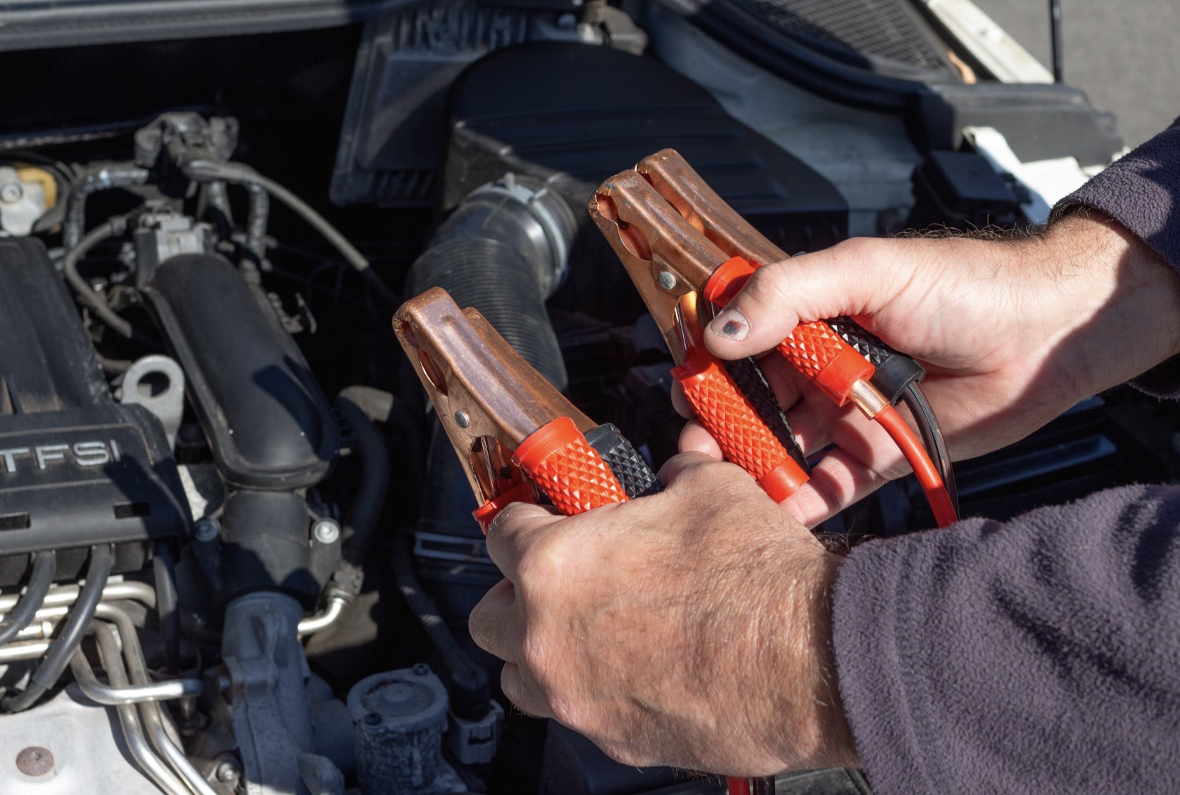 Man, using a set of jumper cables in order to start a car in Rockford, Illinois.
